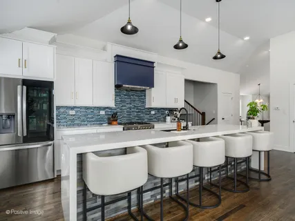 a kitchen with a dining table chairs sink and white cabinets