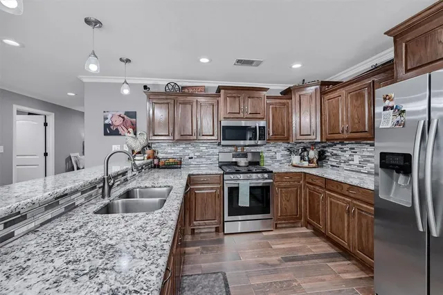 a kitchen with stainless steel appliances granite countertop a sink stove refrigerator and cabinets