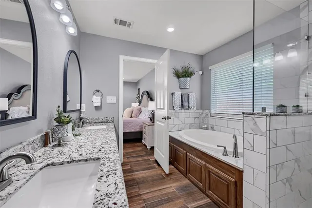 a large bathroom with a granite countertop tub a double vanity sink and a mirror