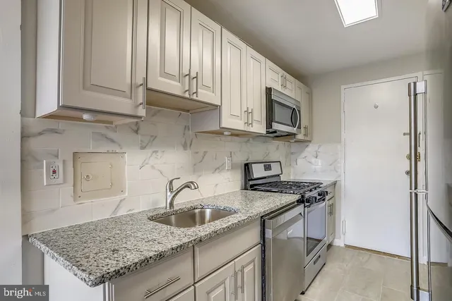 a kitchen with stainless steel appliances granite countertop a sink stove and refrigerator