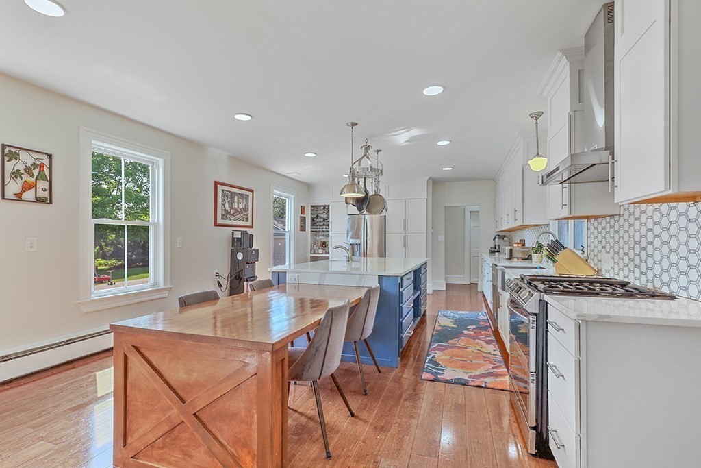28 Maple Street Mendon, MA 01756 - Photo 21 of 39 a dining hall with stainless steel appliances granite countertop a stove a sink a dining table and chairs with wooden floor