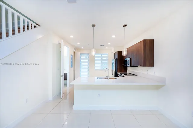 a view of kitchen with kitchen island granite countertop a sink and a refrigerator