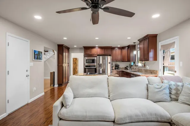 a living room with furniture kitchen view and a wooden floor