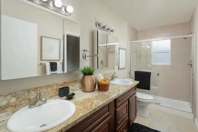 a bathroom with a granite countertop sink a toilet and a shower