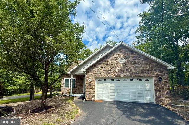 a view of a house with a small yard and a large tree