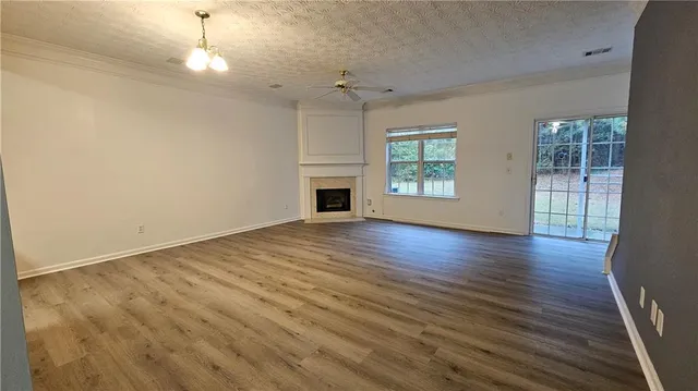 an empty room with wooden floor fireplace and windows