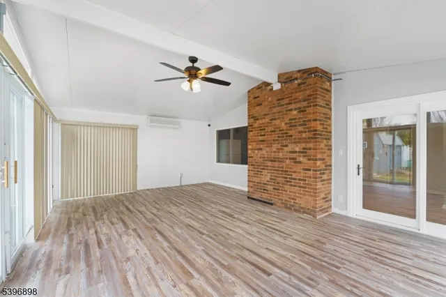 a view of empty room with wooden floor and ceiling fan