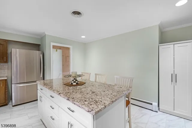 a kitchen with granite countertop a refrigerator and microwave