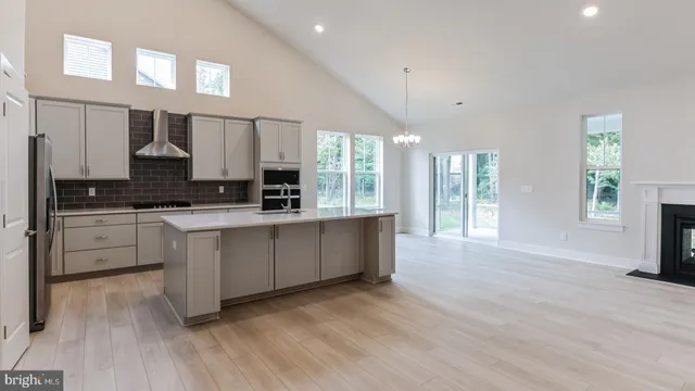 a large kitchen with kitchen island granite countertop a stove a sink a refrigerator and white cabinets with wooden floor