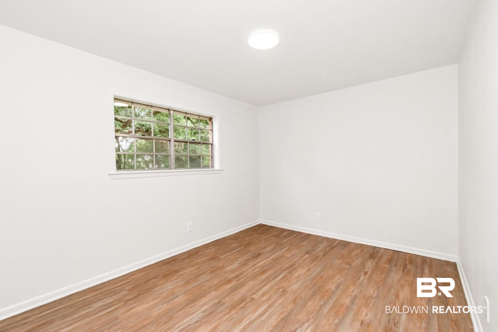 5217 Perin Road Mobile, AL 36693 - Photo 8 of 45 Room featuring light wood-finish flooring, white walls, and a single window with white trim