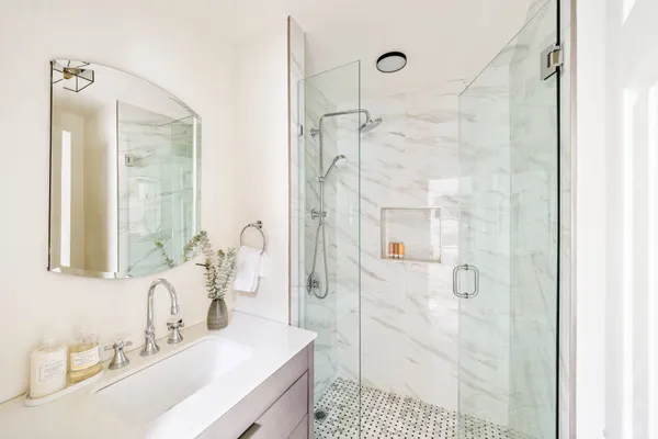 a bathroom with a sink vanity granite shower and a mirror