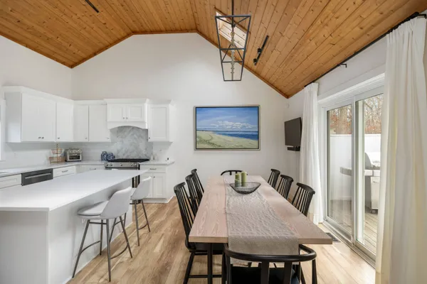 a kitchen with stainless steel appliances granite countertop a stove a refrigerator a dining table and chairs with wooden floor