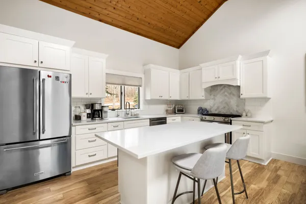 a kitchen with stainless steel appliances a refrigerator a stove a sink dishwasher and a refrigerator with wooden floor