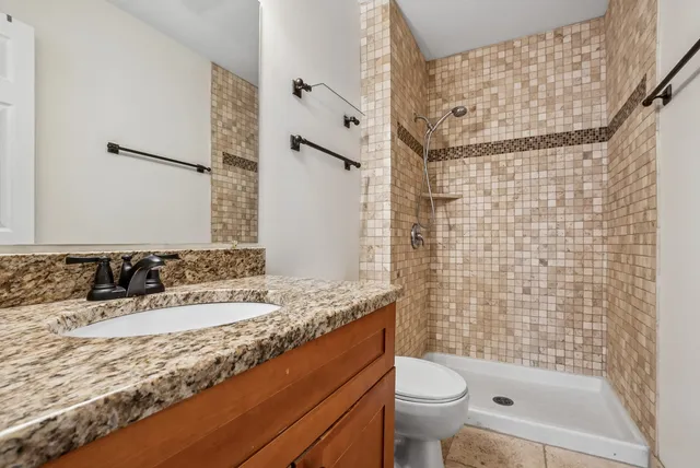 a bathroom with a granite countertop sink toilet and shower