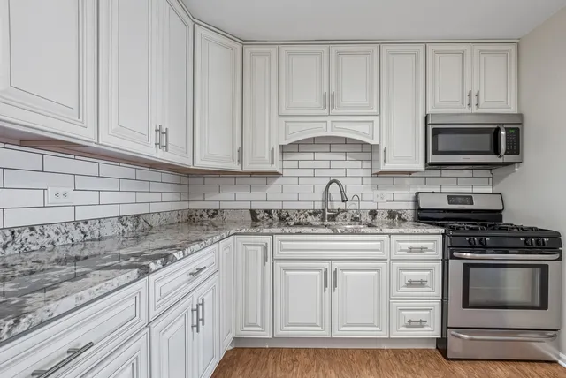 a kitchen with white cabinets and stainless steel appliances