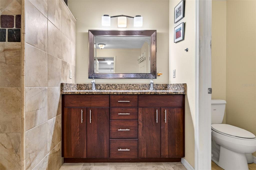 1520 South Keene Road Clearwater, FL 33756 - Photo 31 of 60 a bathroom with a granite countertop sink a toilet and a mirror
