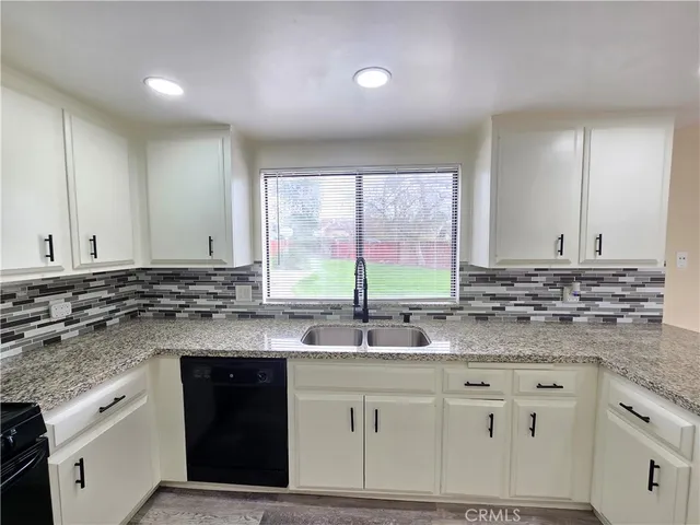 a kitchen with granite countertop a sink and white cabinets