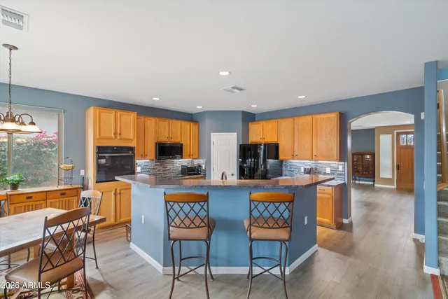 a kitchen with stainless steel appliances kitchen island granite countertop a refrigerator a stove and a sink