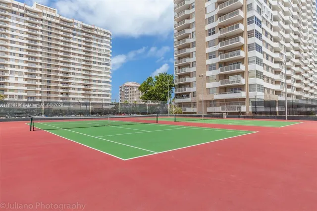 a view of a tennis ground with a large building