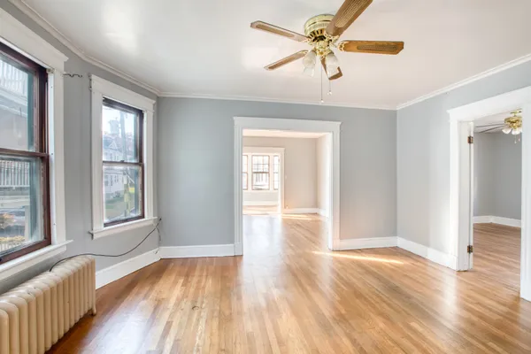 a view of an empty room with window and wooden floor