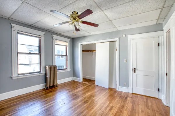 a view of empty room with wooden floor and fan