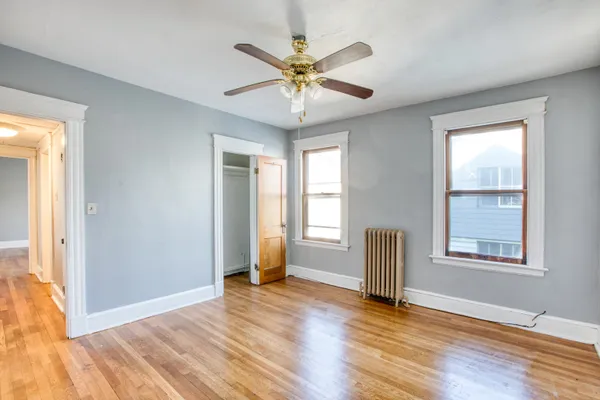 an empty room with wooden floor fan and windows