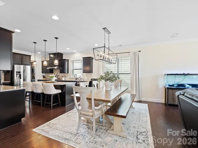 a kitchen with stainless steel appliances kitchen island granite countertop a dining table chairs and a refrigerator