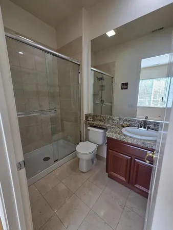 a bathroom with a granite countertop sink toilet a mirror and shower