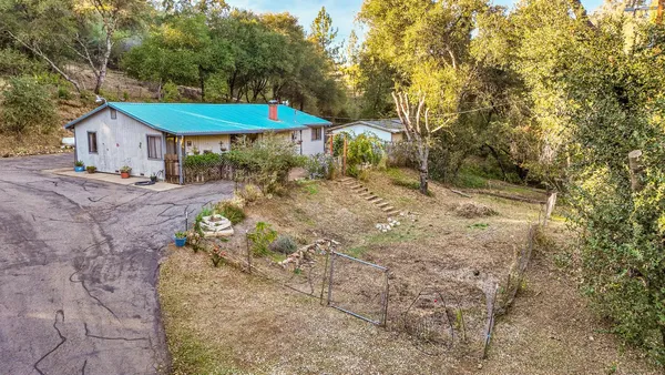 a backyard of a house with table and chairs under an umbrella