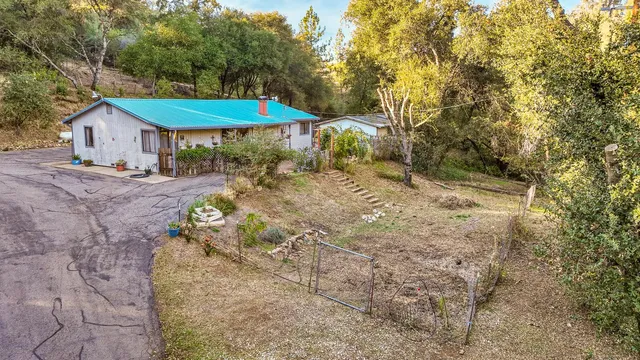 a backyard of a house with table and chairs under an umbrella
