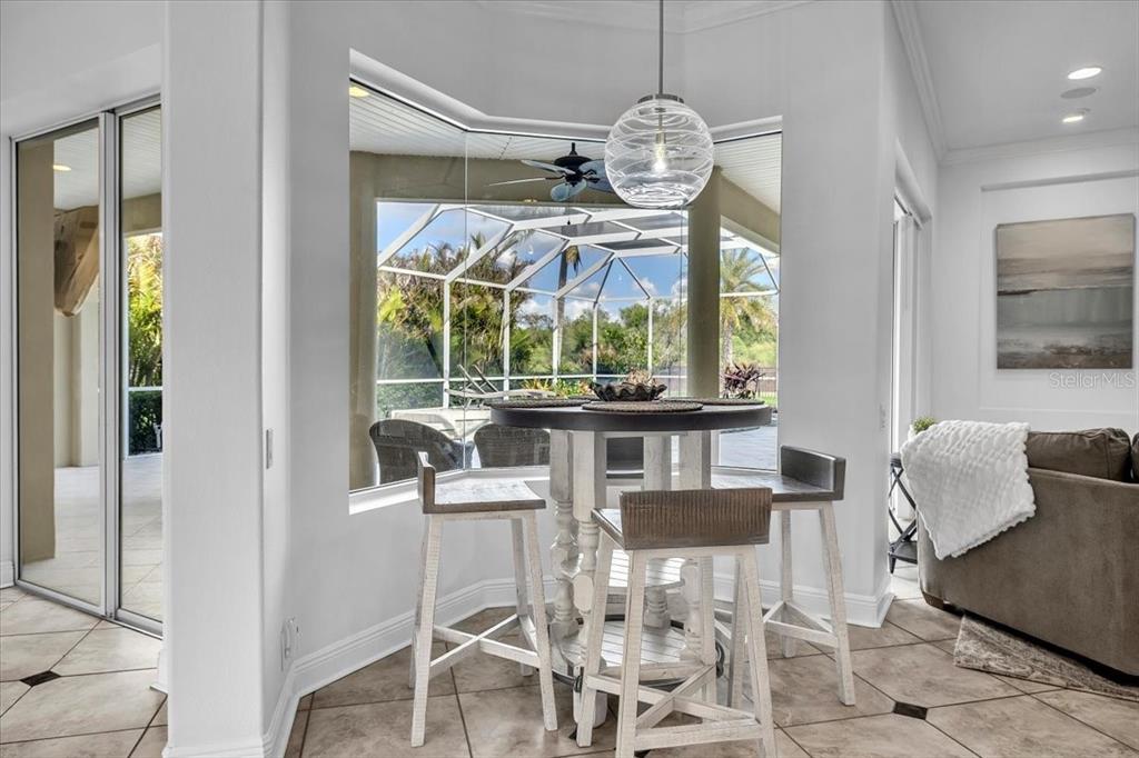 709 Country Meadows Way Bradenton, FL 34212 - Photo 32 of 97 a dining room with wooden floor a chandelier a glass table and chairs