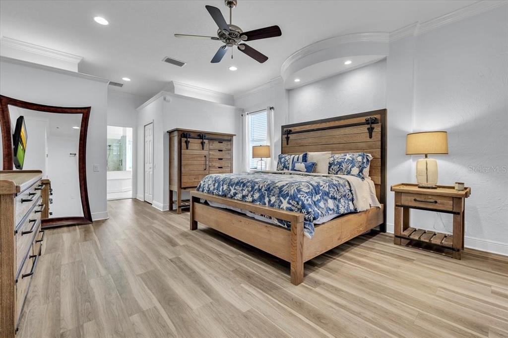 709 Country Meadows Way Bradenton, FL 34212 - Photo 40 of 97 a bedroom with a bed a mirror on dresser and a wooden floor