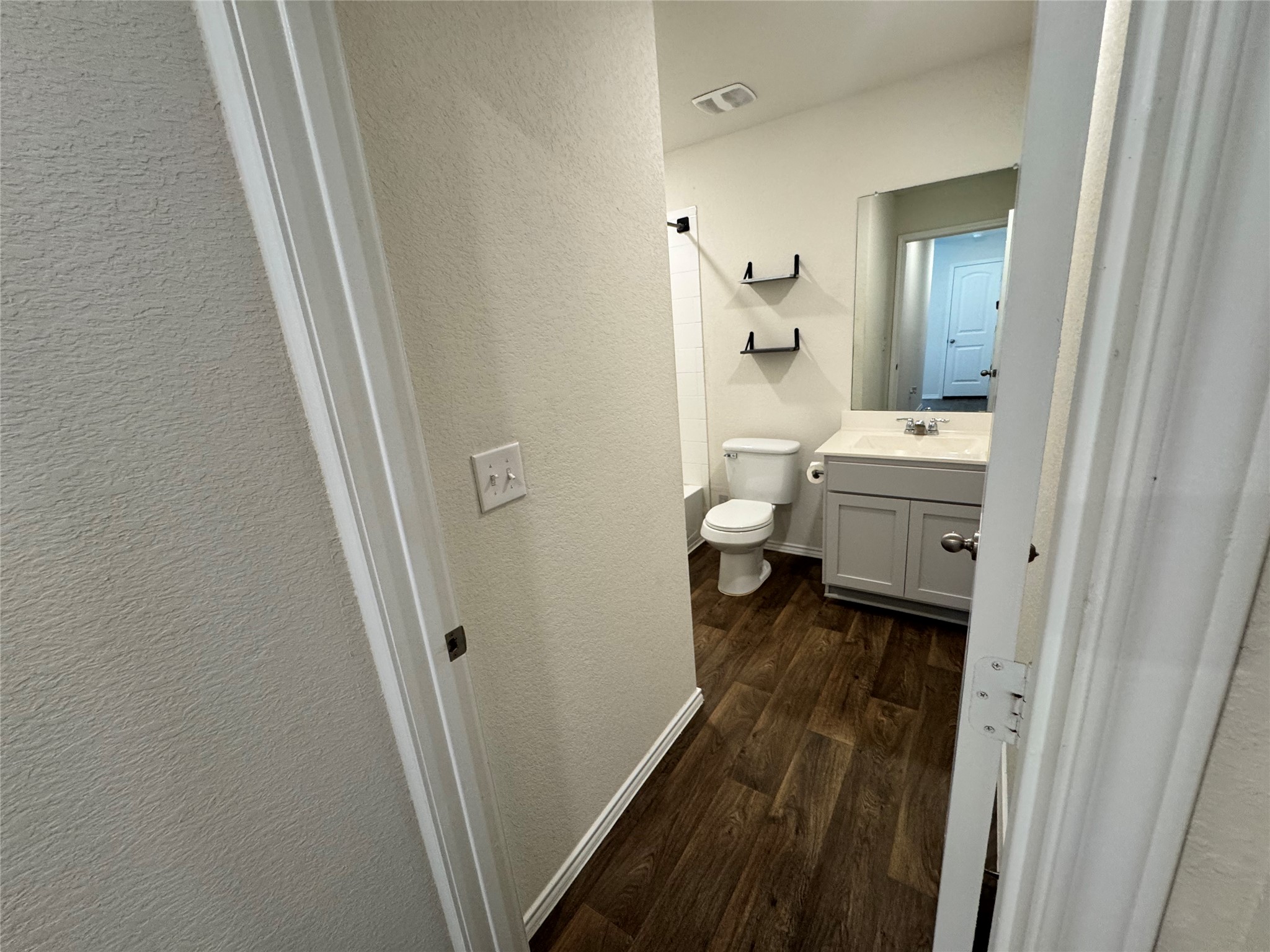 11820 Rush Lane Elgin, TX 78621 - Photo 10 of 31 Rich wood-look flooring extends through this full bathroom featuring a modern vanity and clean design.