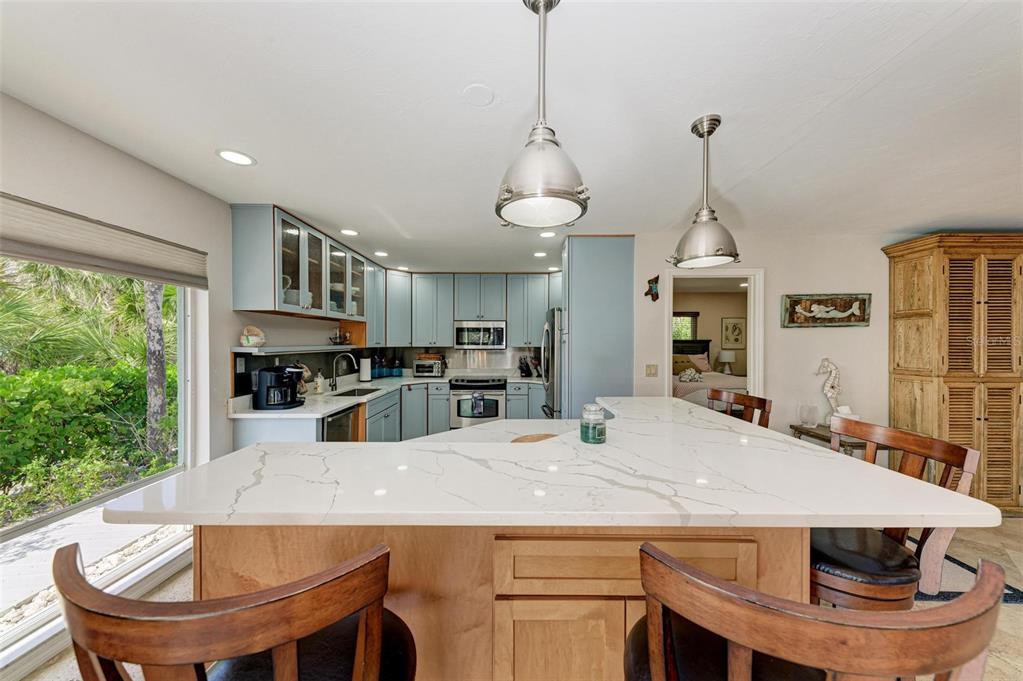 8320 Manasota Key Road Englewood, FL 34223 - Photo 20 of 58 a kitchen with kitchen island a stove a sink a dining table and chairs with wooden floor