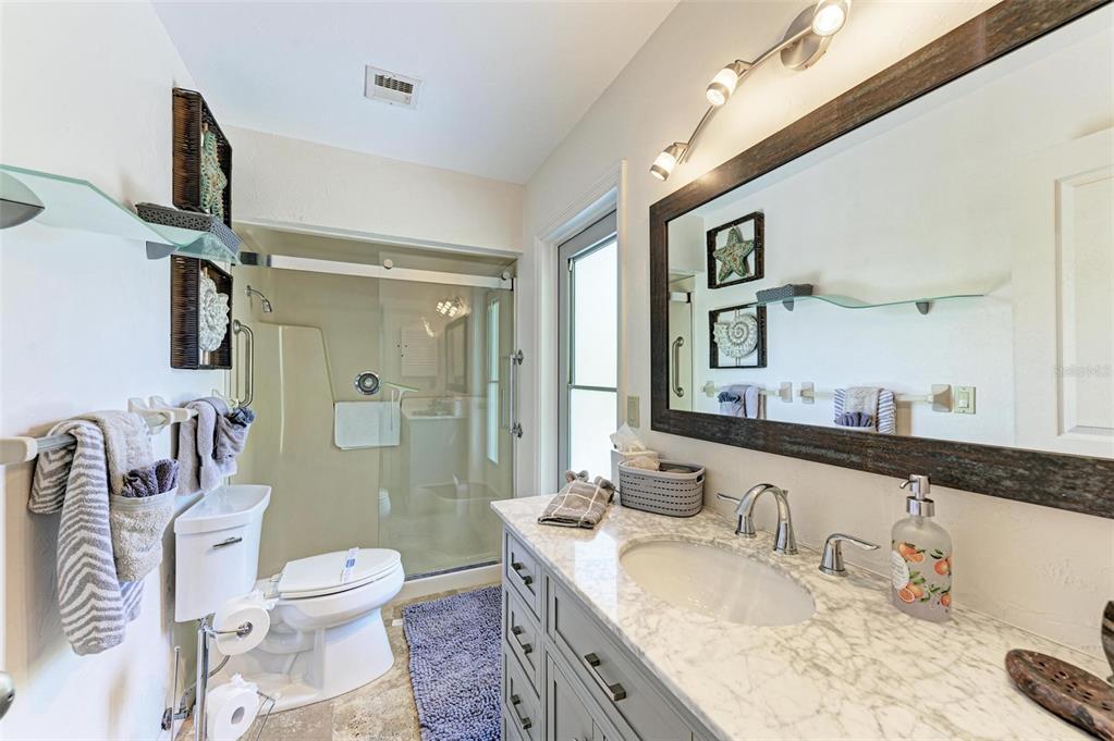 8320 Manasota Key Road Englewood, FL 34223 - Photo 29 of 58 a bathroom with a granite countertop sink a toilet a mirror and shower
