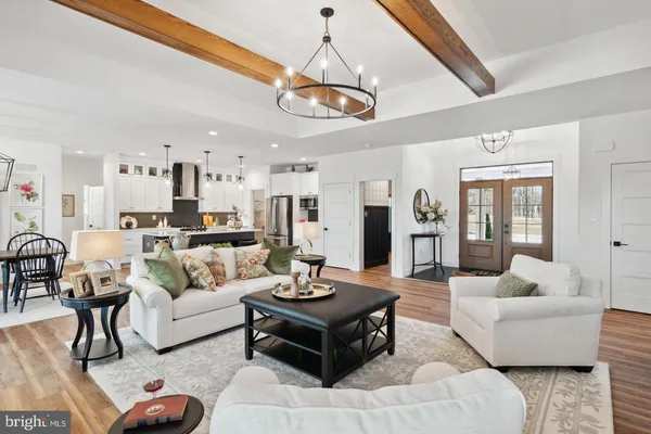 a living room with furniture kitchen view and a chandelier