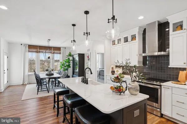 a kitchen with stainless steel appliances a dining table chairs and white cabinets