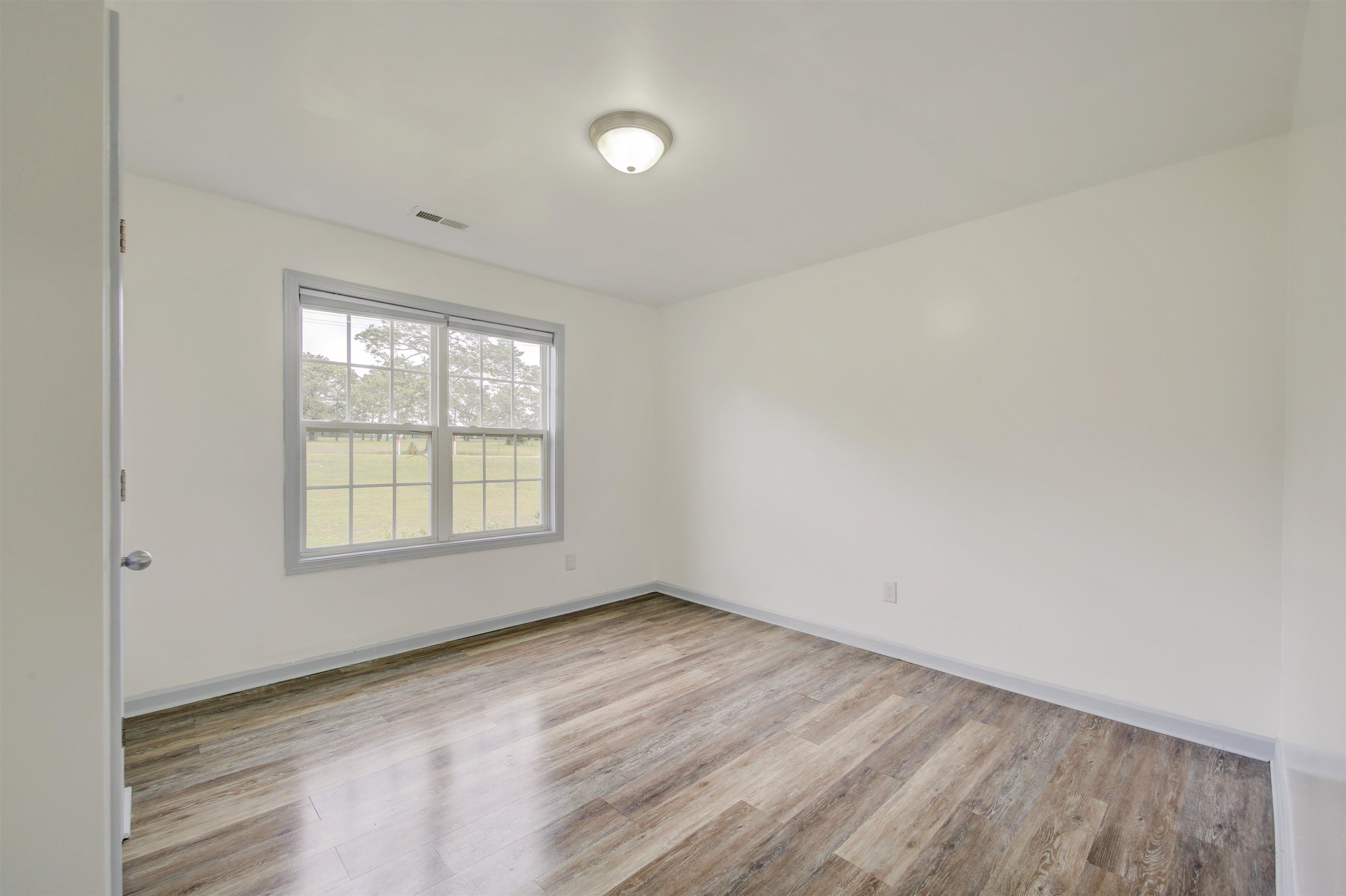 6391 Overhills Road Spring Lake, NC 28390 - Photo 9 of 15 an empty room with wooden floor and windows