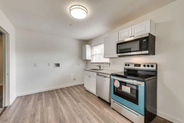 a kitchen with granite countertop cabinets stainless steel appliances and a wooden floor