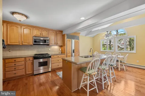 a kitchen with stainless steel appliances granite countertop a stove top oven a sink a dining table and chairs with wooden floor