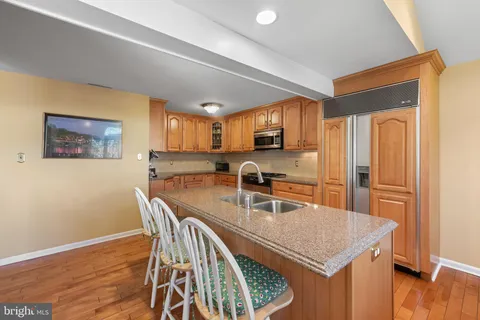 a kitchen with stainless steel appliances granite countertop a stove a refrigerator a sink a dining table and chairs with wooden floor