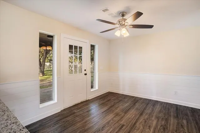 an empty room with wooden floor closet and windows