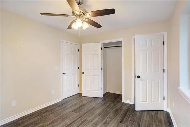 an empty room with wooden floor fan and windows