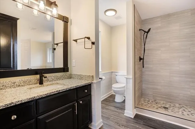 a bathroom with a granite countertop sink toilet a mirror and shower
