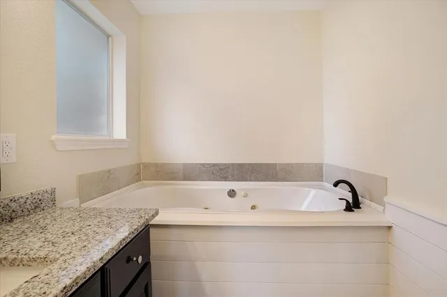 a bathroom with a granite countertop sink and bathtub
