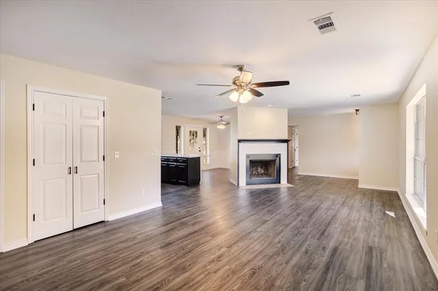 an empty room with wooden floor fireplace and windows