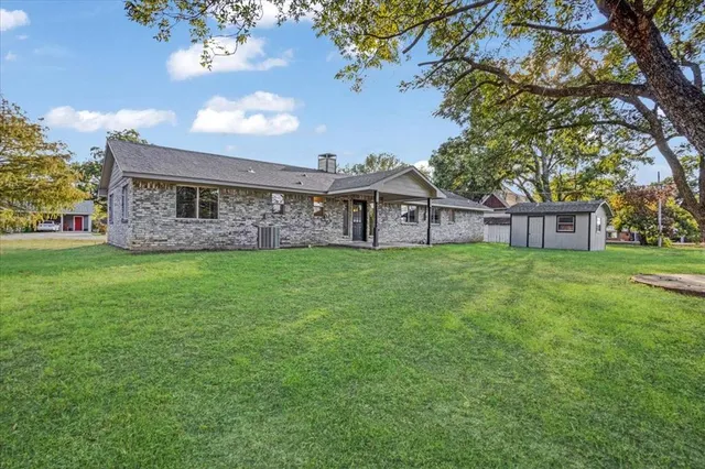 a view of a house with a big yard and large tree