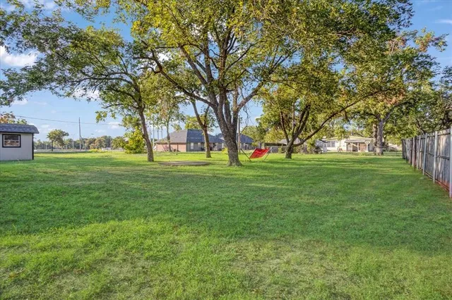 a view of grassy field with benches and trees all around