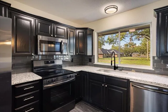 a kitchen with granite countertop stainless steel appliances a sink stove and cabinets