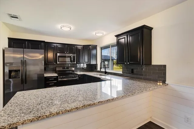 a kitchen with stainless steel appliances granite countertop a sink a stove and a refrigerator with wooden floor